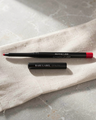 Bare Label Beauty Automatic Lip Liner in Scarlet – matte red pencil with black tube on beige fabric